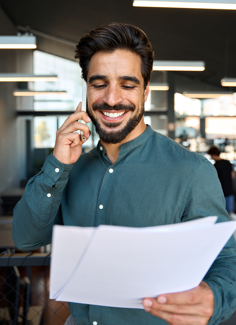 Smiling business man holding papers making call